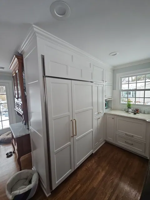 Kitchen with cabinets sprayed white, doors rehung, and fresh wall paint above the counters.