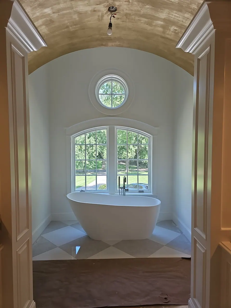 Arched tub nook with round window, ceiling and trim painted white