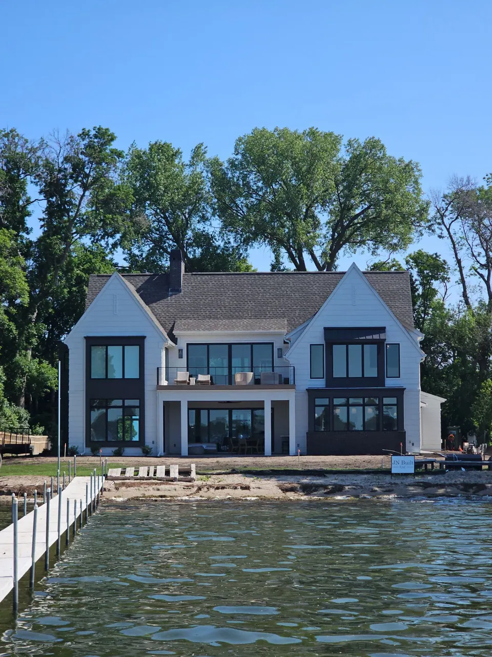Modern farmhouse on a lakeshore with white siding, painted by Brushtek