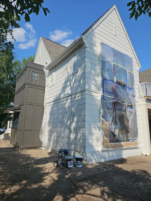 Modern two-story lake home with white painted siding and black window frames, photographed from the yard.