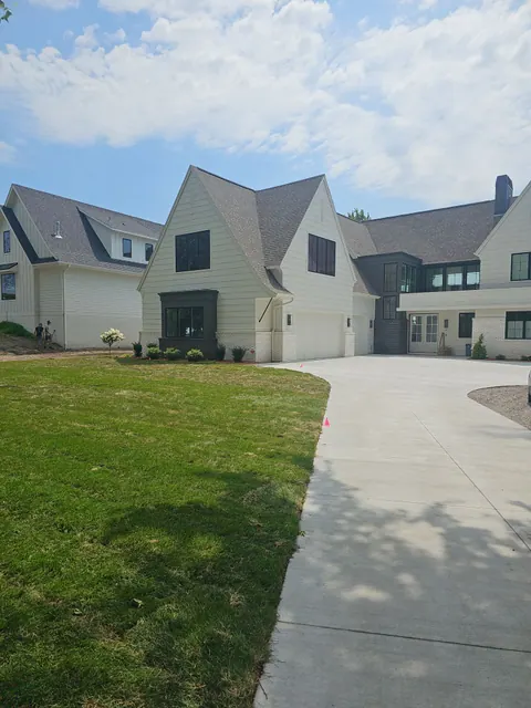 Two-story custom home with white painted siding and dark trim, viewed from the driveway.