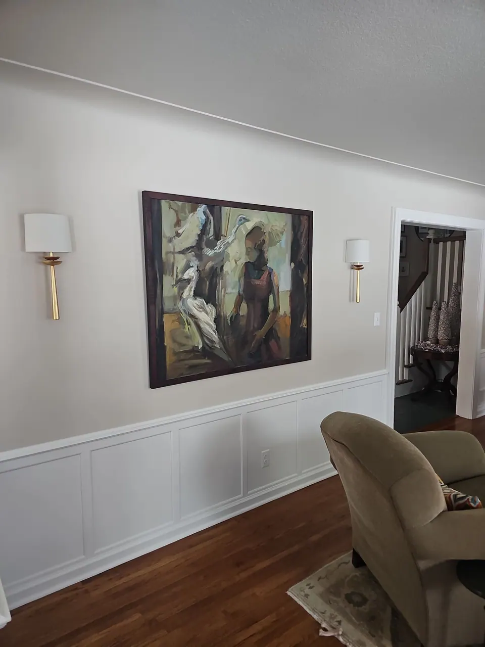 Hallway with painted wainscoting and wall sconces
